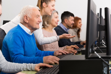 Eine Gruppe Menschen sitzt vor Computerbildschirmen